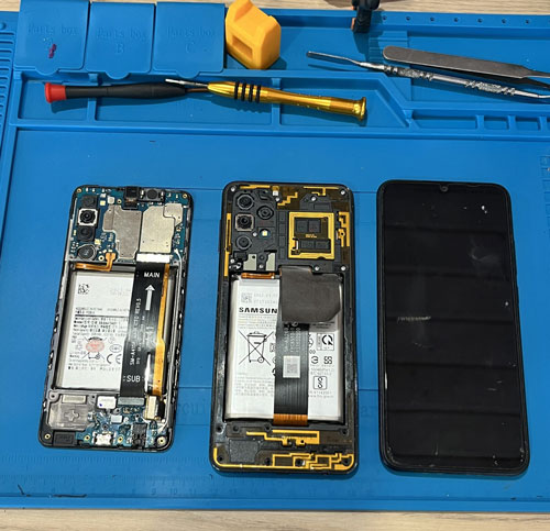 Pièces d’un téléphone démonté disposées sur un tapis de réparation