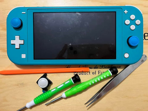 Switch Lite avec différents outils et un joystick en pièce détaché